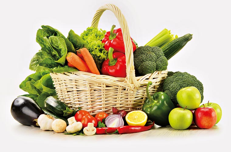 Ausgewogene vegane Ernährung: Korb mit frischem Gemüse und Obst, darunter Brokkoli, Paprika, Karotten, Äpfel, Tomaten, Zwiebeln und Salat.